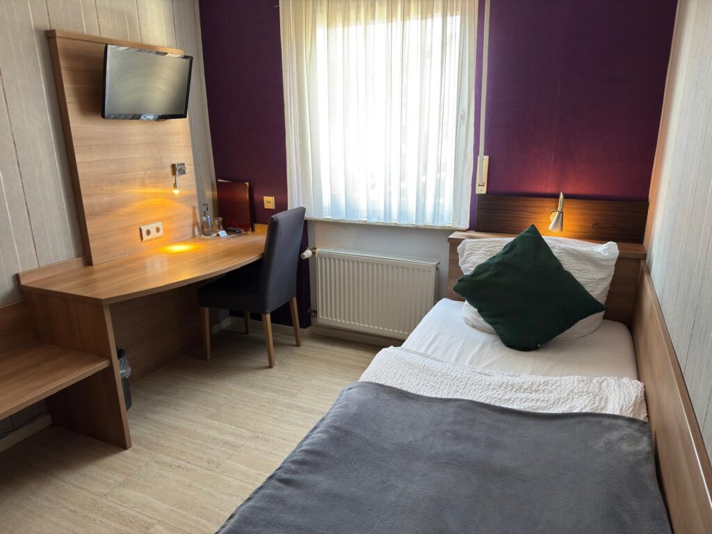 Einzelzimmer mit Bett, Schreibtisch und Fernseher